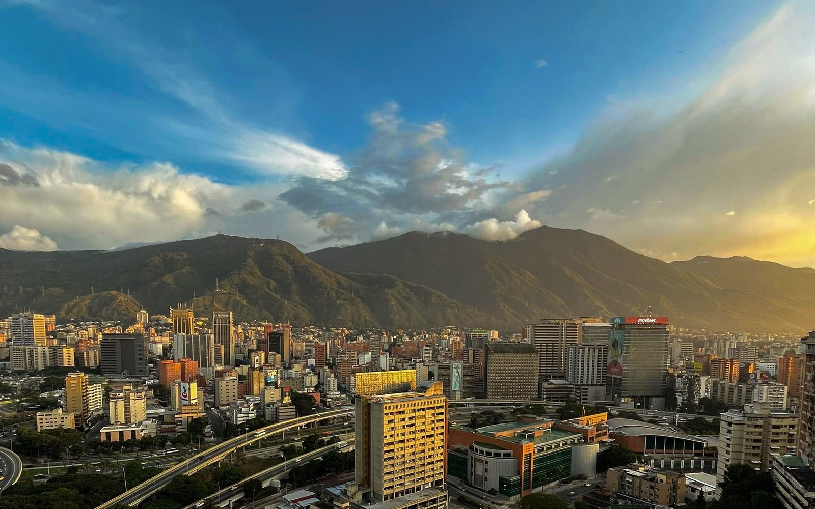 Vista urbana de Caracas con El Ávila al fondo durante el atardecer.